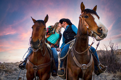 A couple kissing side-by-side on horses
